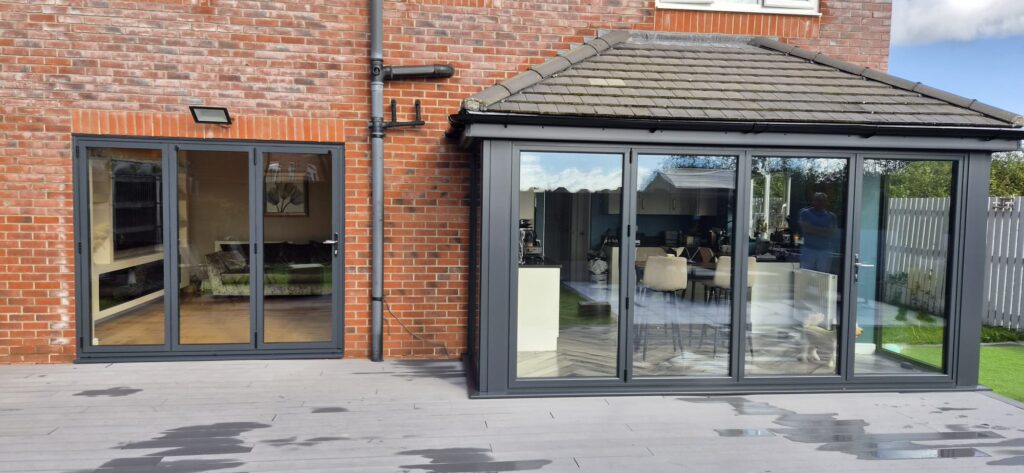 Wide view of matching grey bi-fold doors on the house and extension in Prestatyn