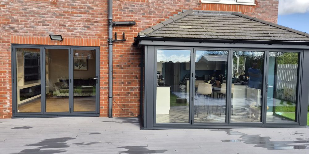 Wide view of matching grey bi-fold doors on the house and extension in Prestatyn